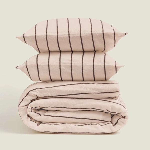 Stack of pink striped bedding on a light beige background
